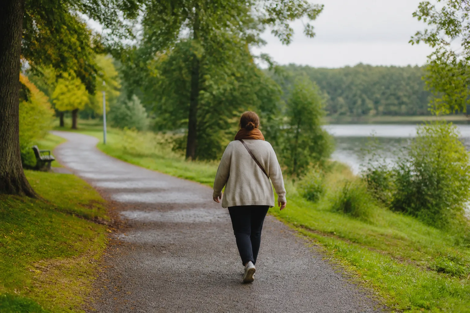 En person tar en vardagspromenad på en grön gångväg vid vatten